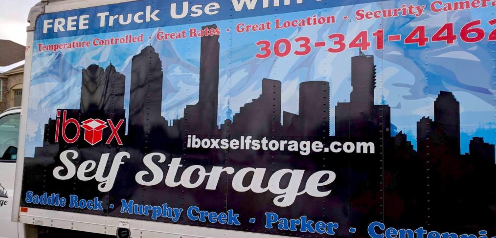 Moving truck with advertising for "ibox self storage" featuring contact info and an image of a city skyline.