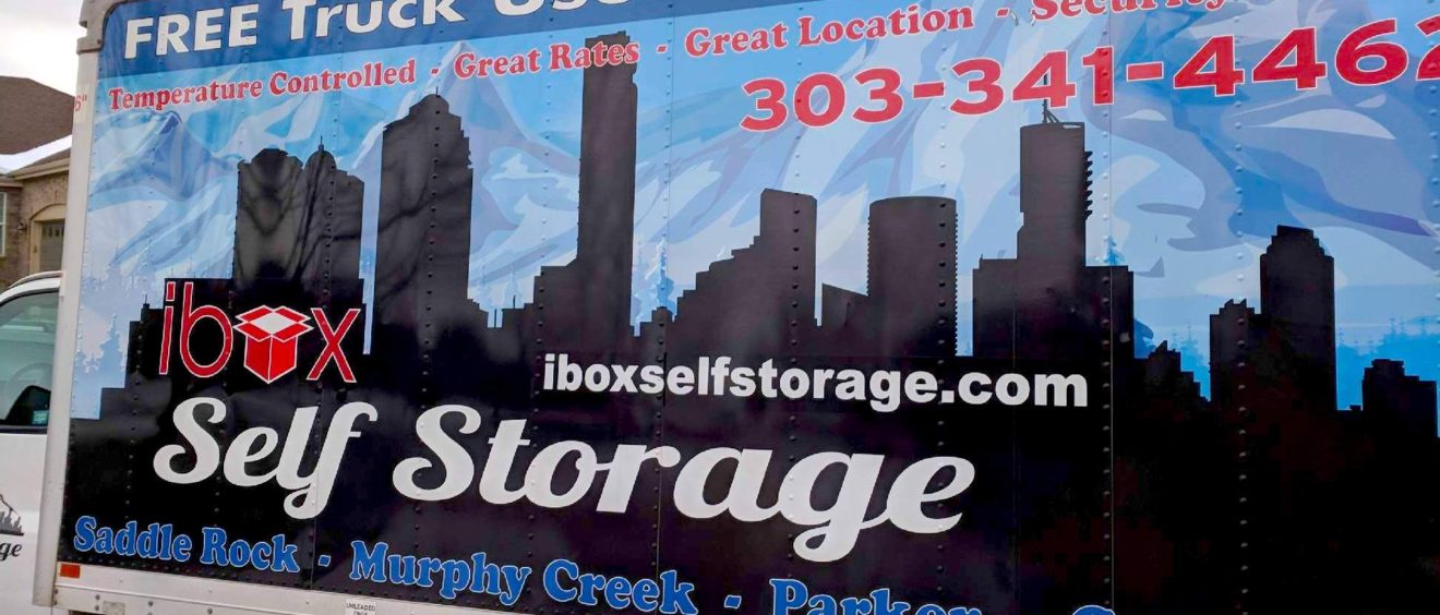 Moving truck with advertising for "ibox self storage" featuring contact info and an image of a city skyline.