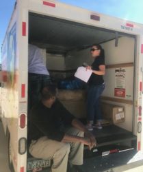 A woman and a man organizing boxes in the back of a rental truck.
