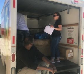 A woman and a man organizing boxes in the back of a rental truck.