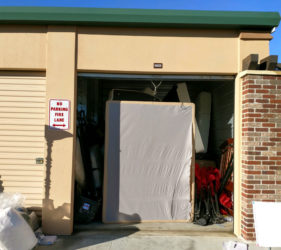 Storage unit with an open door revealing items like mattresses; a "no parking fire lane" sign is visible on the left.