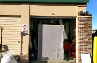 Storage unit with an open door revealing items like mattresses; a "no parking fire lane" sign is visible on the left.