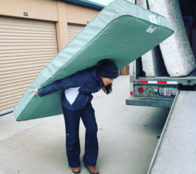 A person lifting a mattress from a vehicle on his back