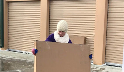 A person standing in front of a cardboard box.