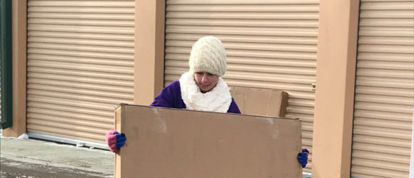 A person standing in front of a cardboard box.