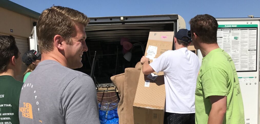 A group of people loading boxes into the back of a truck.