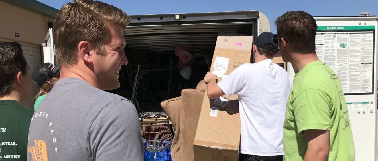 A group of people loading boxes into the back of a truck.