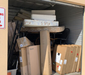A garage with boxes and furniture stacked in it.