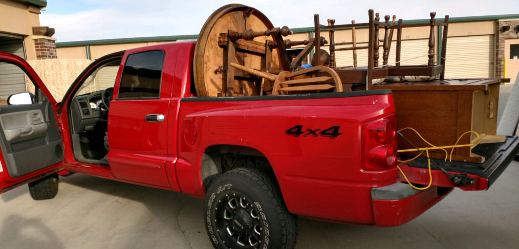 A red truck with a large wooden wheel in the back.