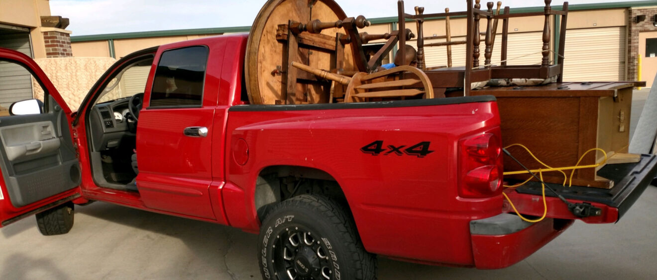 A red truck with a large wooden wheel in the back.