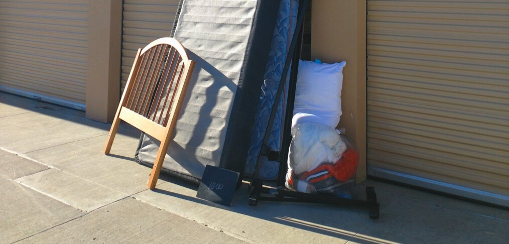 A pile of mattresses and pillows next to a chair.