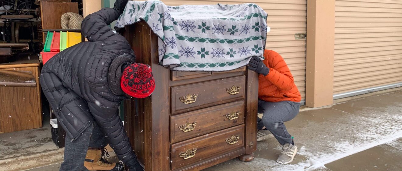 Two people are hiding behind a dresser.