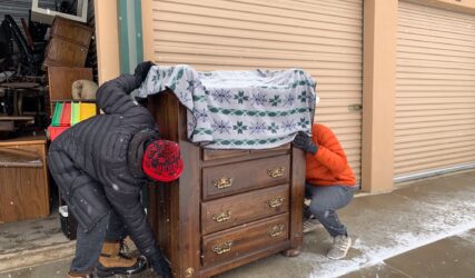 Two people are pushing a dresser into the garage.