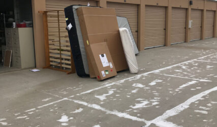 A pile of furniture sitting in front of a storage unit.