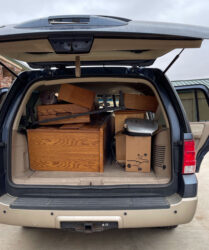 A van with the back door open and a lot of furniture in it.