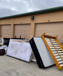 A pile of mattresses and other items outside of a storage unit.