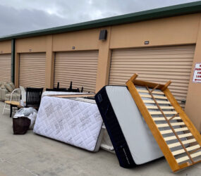 A pile of mattresses and other items outside of a storage unit.