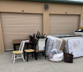 A pile of furniture sitting outside of a storage unit.