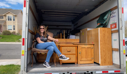 A woman sitting on the back of a moving truck.