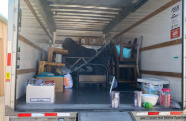 A truck with boxes and furniture in the back.