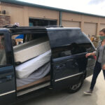 A man loading a truck with mattresses.