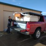 A man loading furniture into the back of his truck.