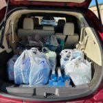 A car trunk filled with bags of groceries and water.