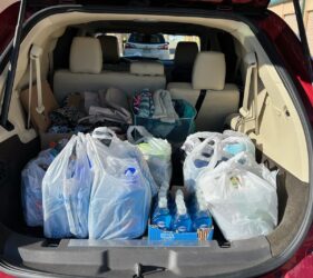 A car trunk filled with bags of groceries and water.