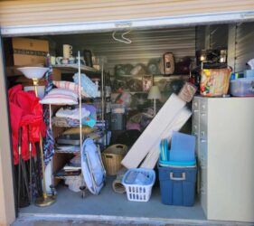 A garage with many items in it and the door open.