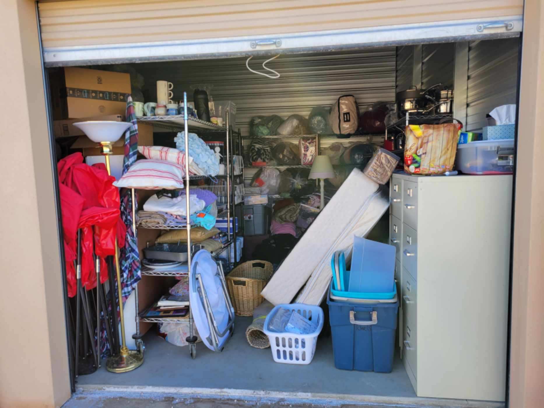 A garage with many items in it and the door open.