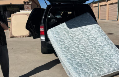 A man standing next to a truck with an unmade mattress.