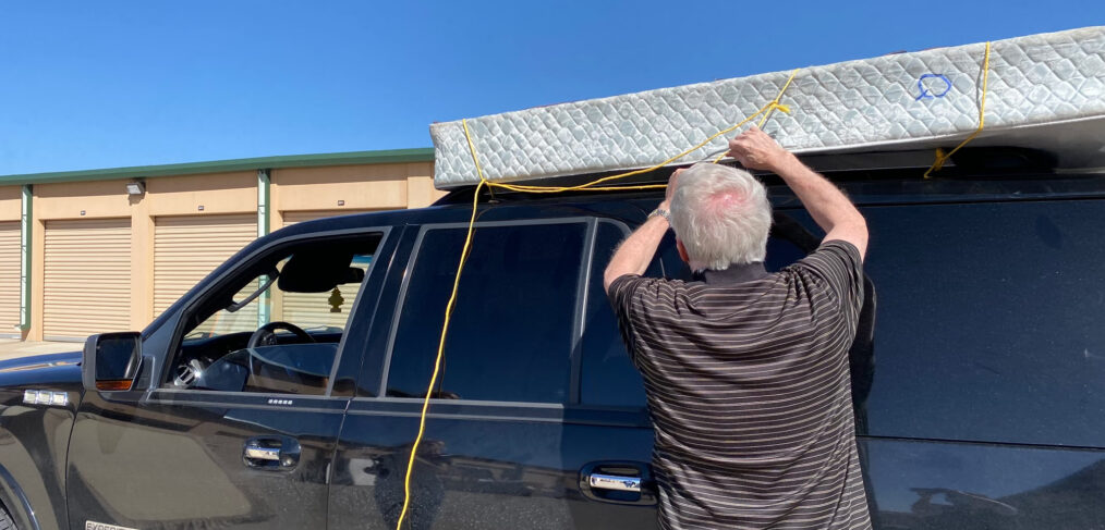 A man is hanging up the roof of his truck