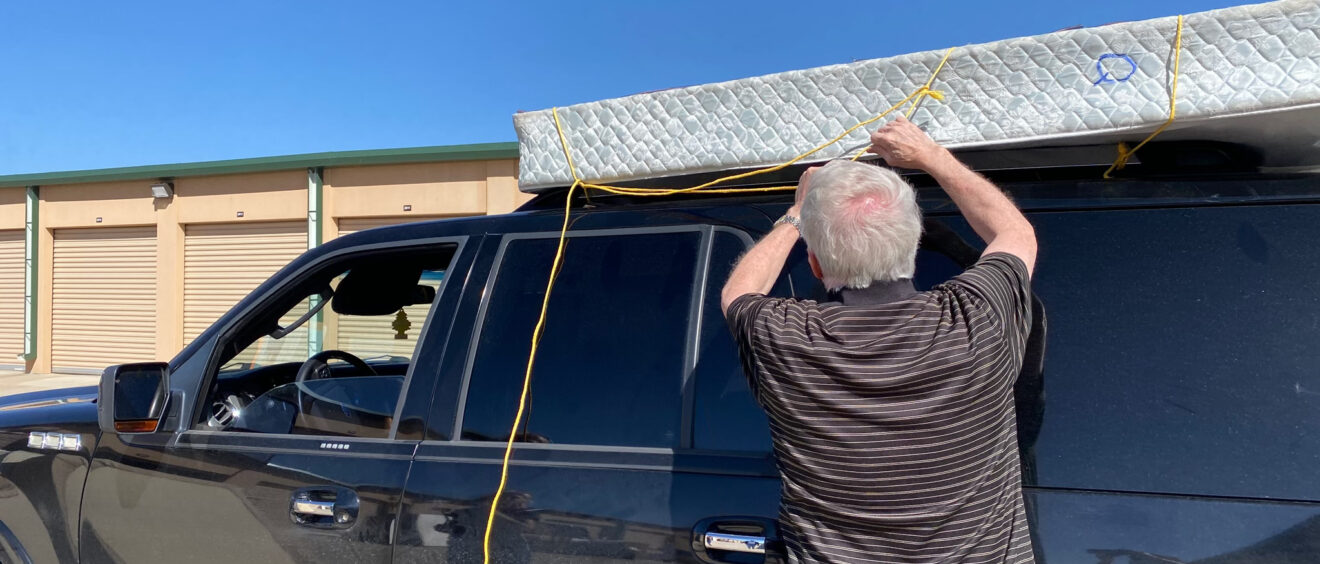 A man is hanging up the roof of his truck