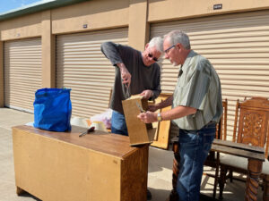 Two men are looking at a box in front of a storage unit.