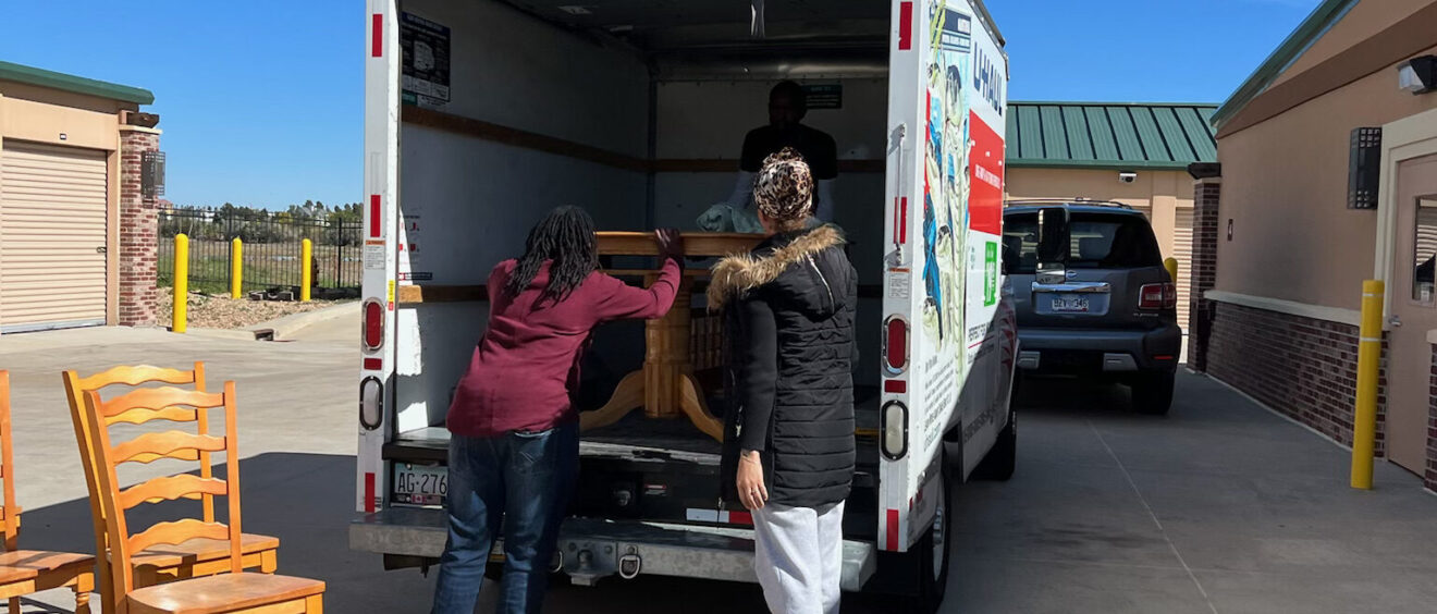 A group of people unloading furniture from the back of a truck.