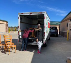 A group of people unloading furniture from the back of a truck.