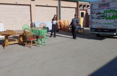 A woman standing next to a truck with furniture.