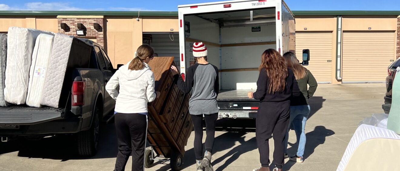 A group of people loading furniture into the back of a truck.