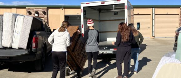 A group of people loading furniture into the back of a truck.