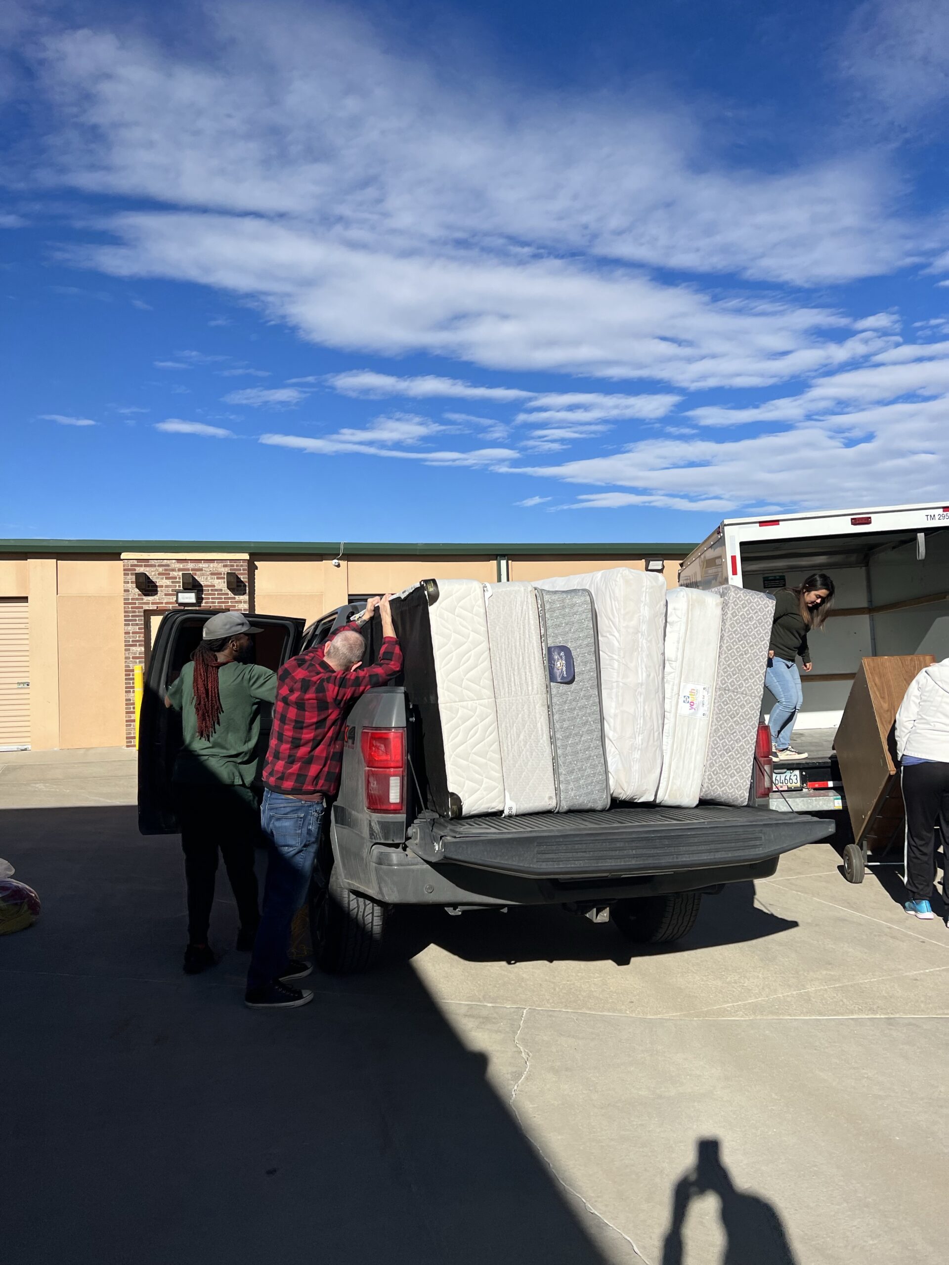 A man and woman loading mattresses into the back of a truck.
