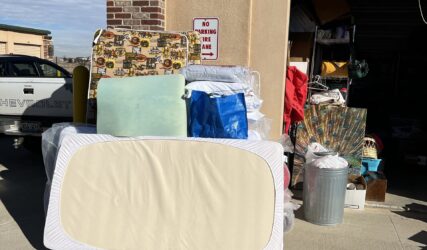 A pile of mattresses and pillows in front of a garage.