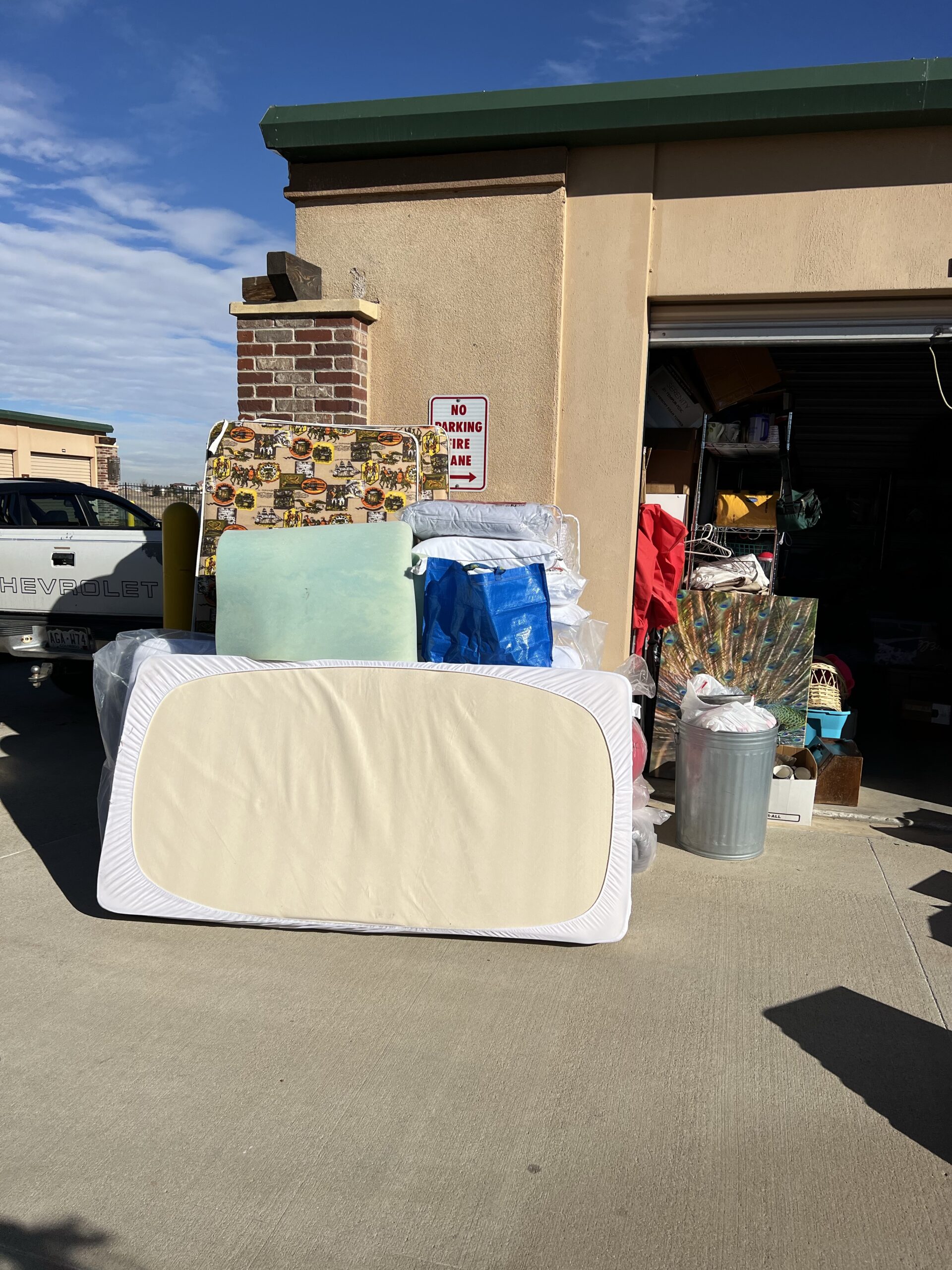 A pile of mattresses and pillows in front of a garage.