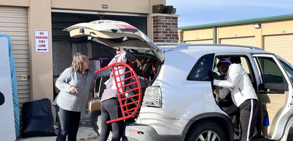 A group of people loading furniture into the back of a car.